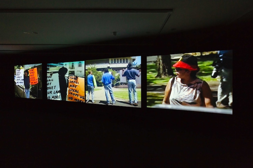 Four screens with scenes from Vernon Ah Kee's videowork tall man