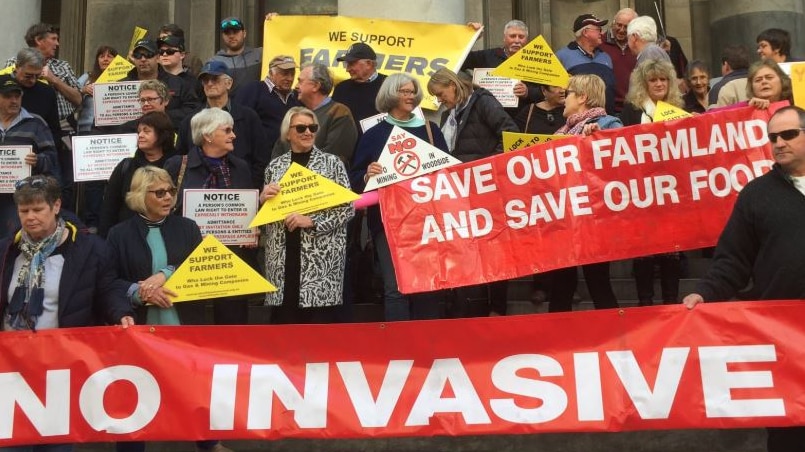 A group holding signs that say "We Support Farmers" and "Save Our Farmland" on the steps of Adelaide's Parliament House.