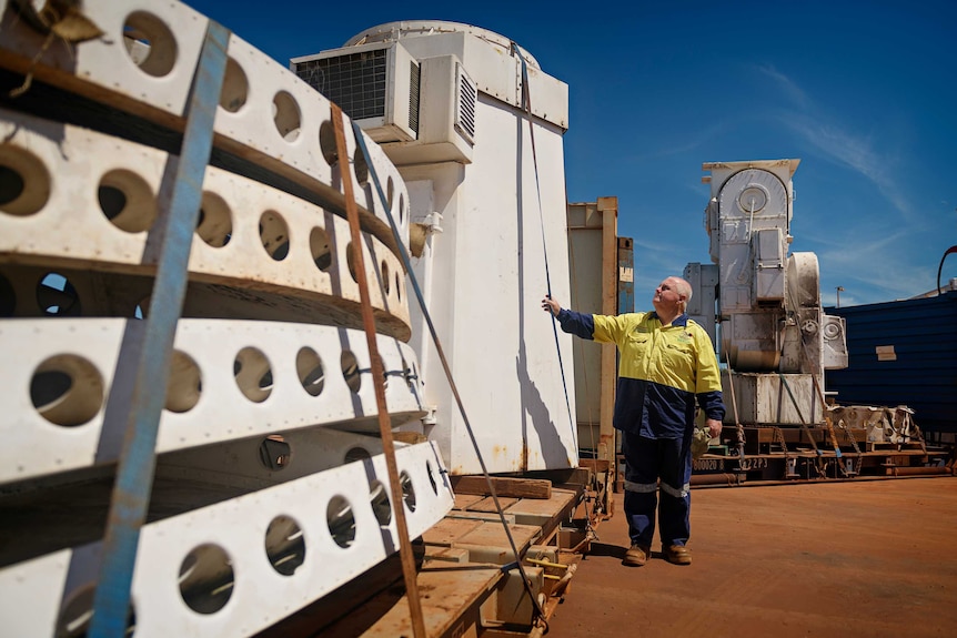 Arnhemland Historical Society's Dave Suter looking up at the pieces of the satellite tracker on a wharf.