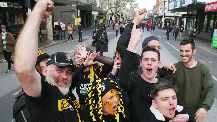 tigers fans celebrate in the middle of a street in melbourne.