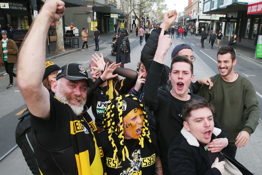 tigers fans celebrate in the middle of a street in melbourne.