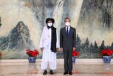 中国外交部长站在阿富汗塔利班政治领袖旁边。