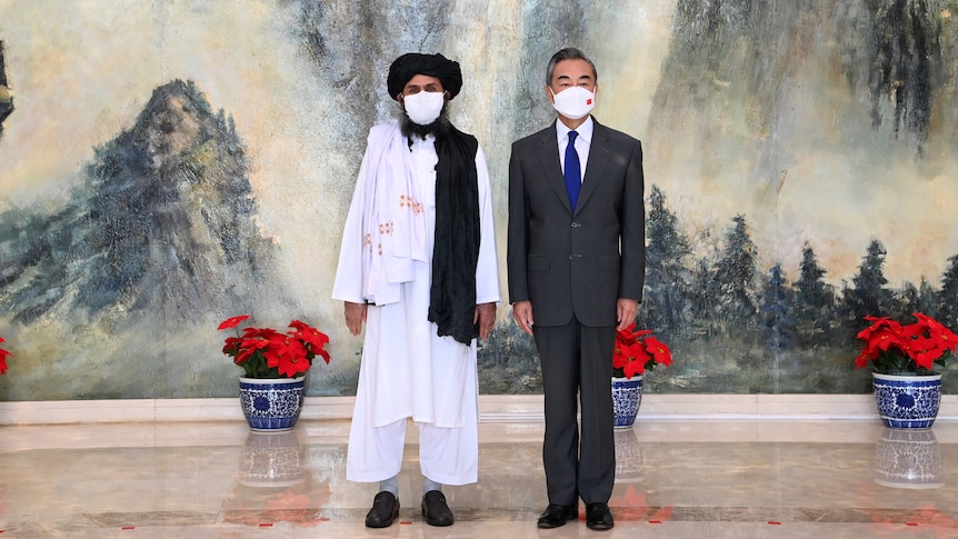 中国外交部长站在阿富汗塔利班政治领袖旁边。