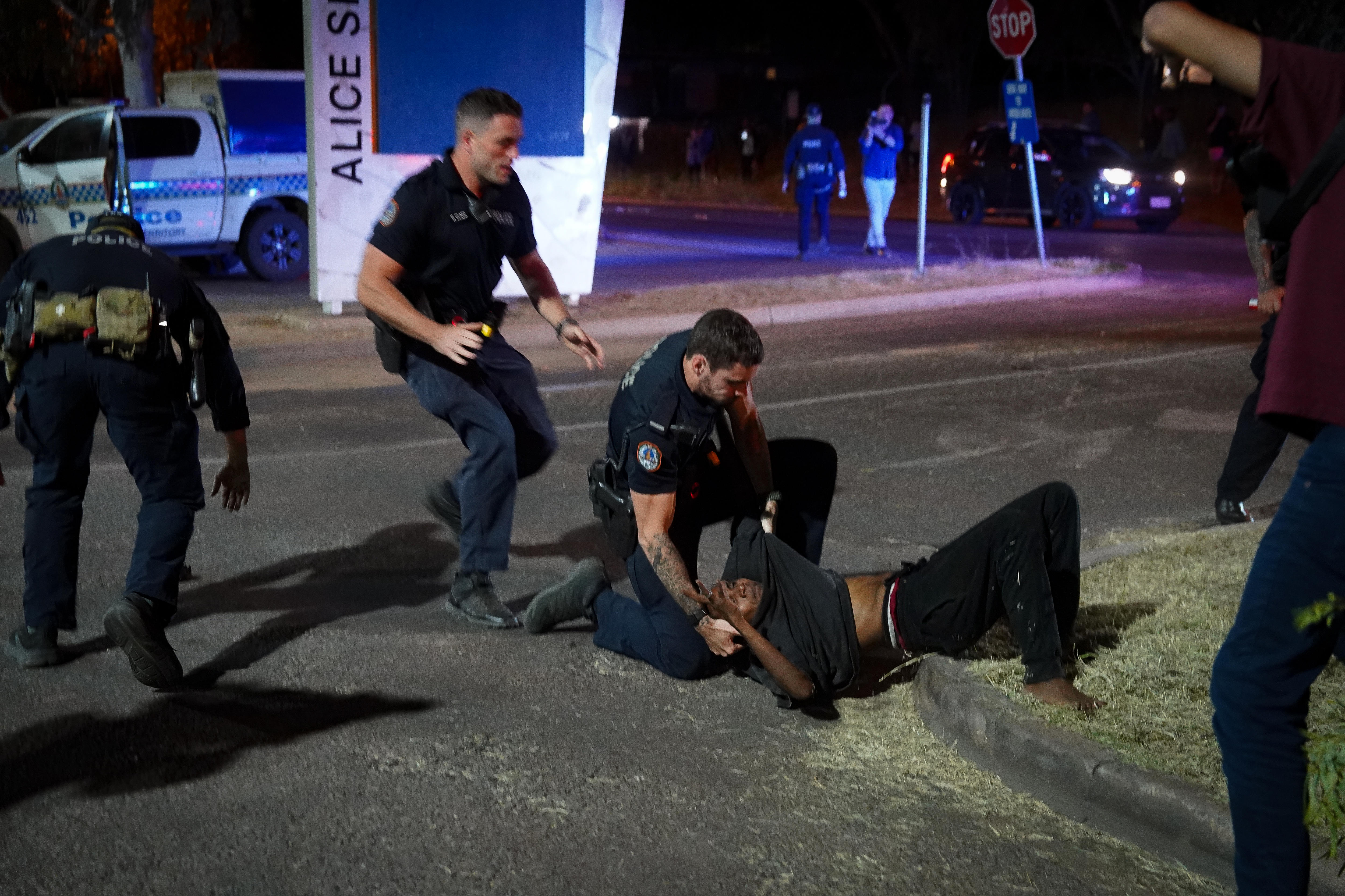 Una persona es arrestada por dos agentes de policía afuera del Hospital Alice Springs durante la noche.