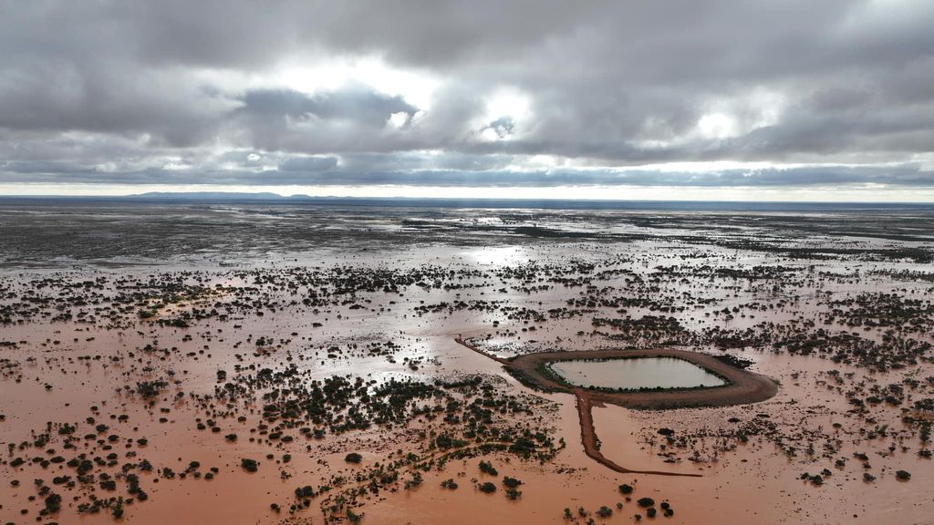 A sweeping view of an outback property with brown water covering most of it.