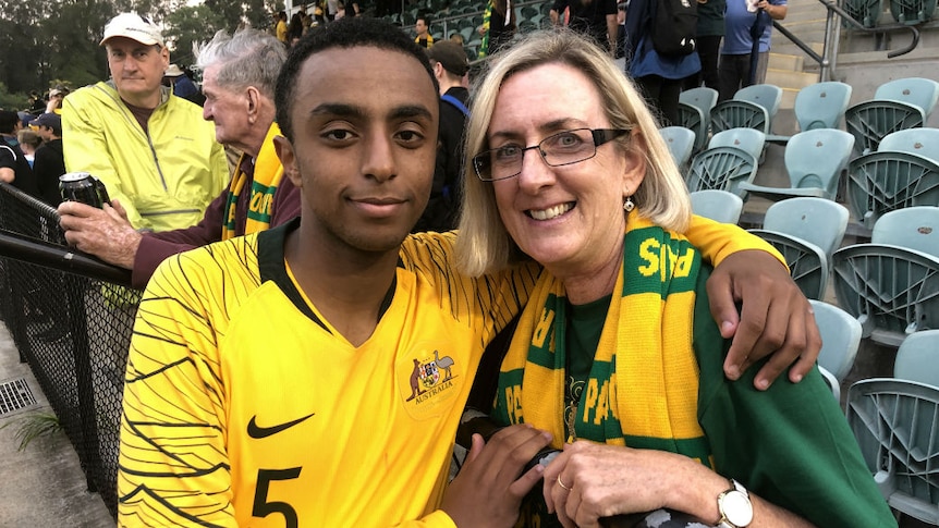 A young man in a football jersey embracing a woman.