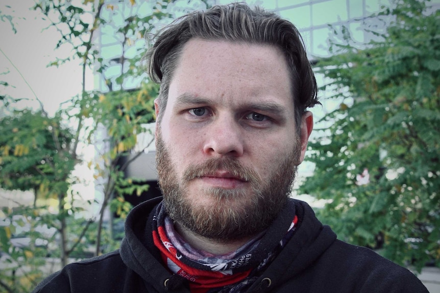 A man looking serious standing in a park