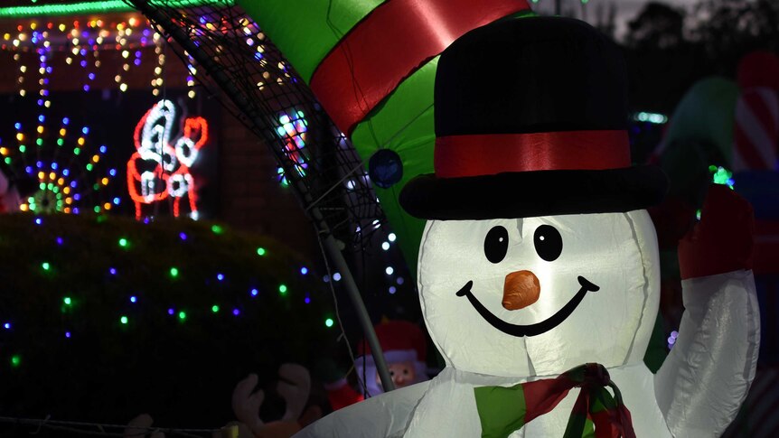 An inflatable snowman decoration in a suburban front yard.