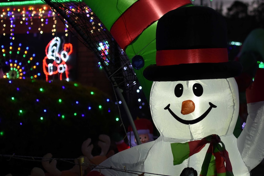 An inflatable snowman decoration in a suburban front yard.