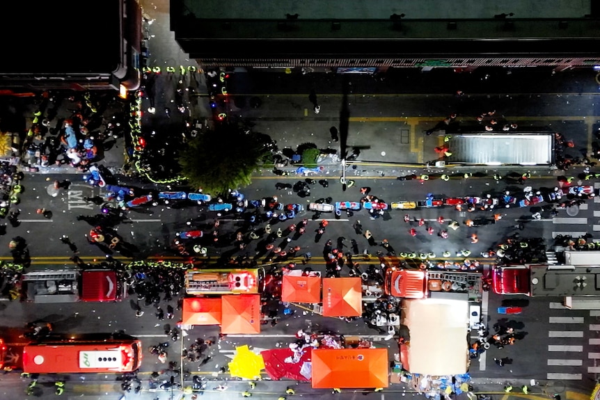 A birds eye view of a street crowded with people and ambulances