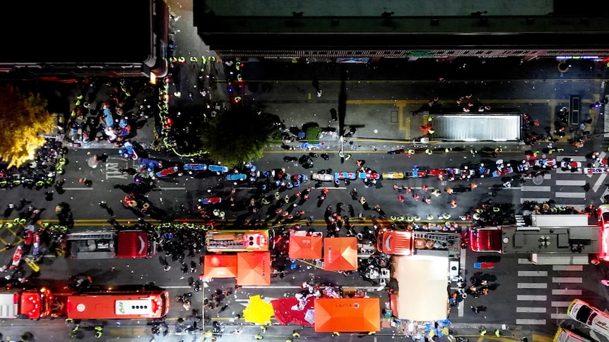 A birds eye view of a street crowded with people and ambulances