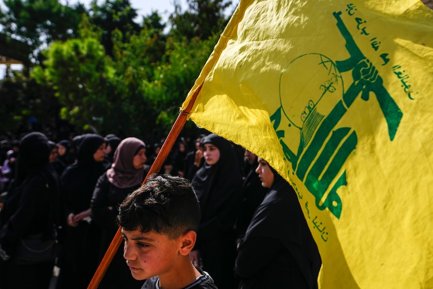 People attend the funeral procession of Hezbollah fighter.