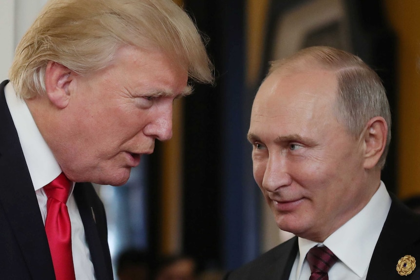 US President Donald Trump speaks to President Vladimir Putin, who is smiling.