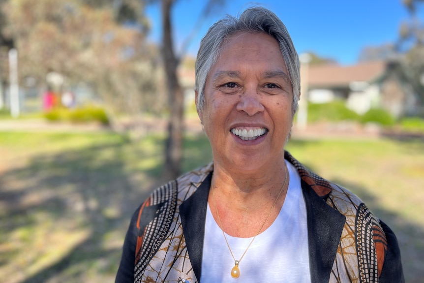 A woman with grey hair smiles at the camera 