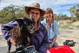 Geoff Lambert, with his arm around an excited dog, and Irene Sher on a quadbike next to Pooncarie's town weir