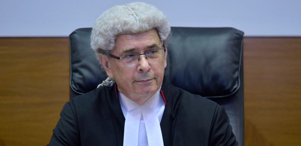 O juiz Southwood está sentado no tribunal vestido com sedas.