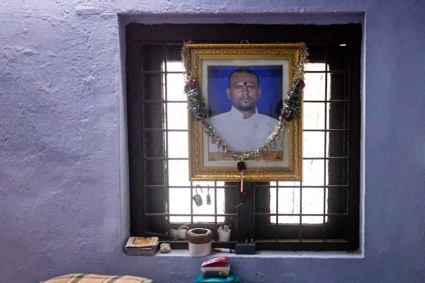 A photo of an Indian man in a gold frame hanging in the window