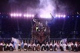 a 10m tall mechanical bull stands over performers in a stadium surrounded by flags