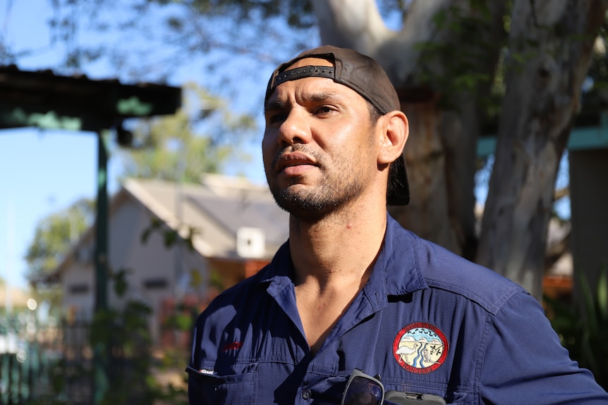 Man stands confidently wearing blue drill shirt and a cap back to front