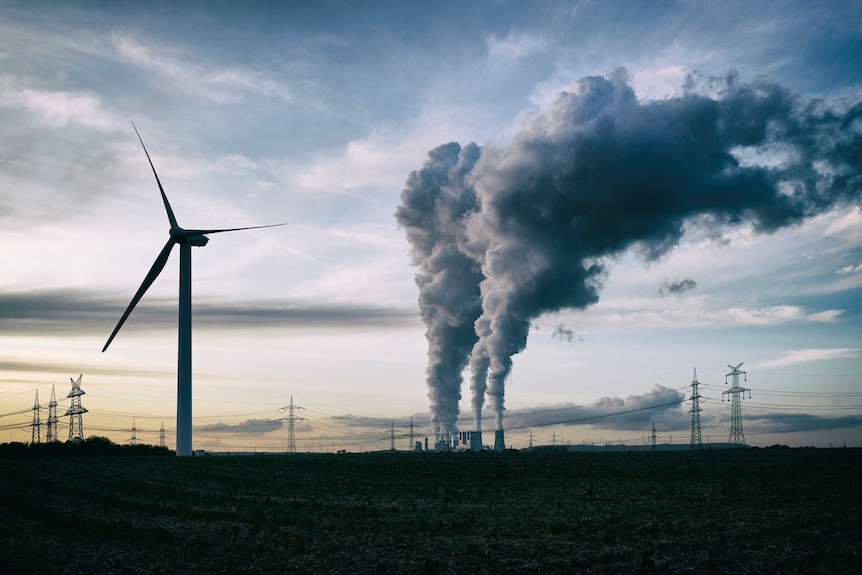 A coal-fired power plant next to wind turbines.