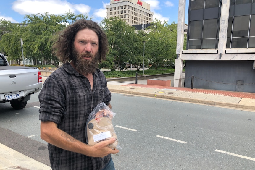 A man holding a baseball cap in an evidence bag.