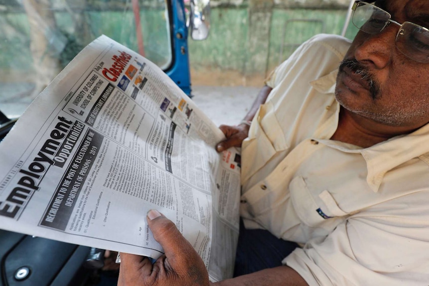 A man in Sri Lanka reads a newspaper in a taxi
