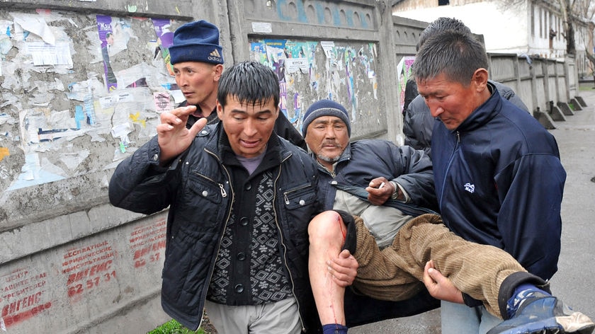 Kyrgyz opposition supporters carry an injured man away from protests