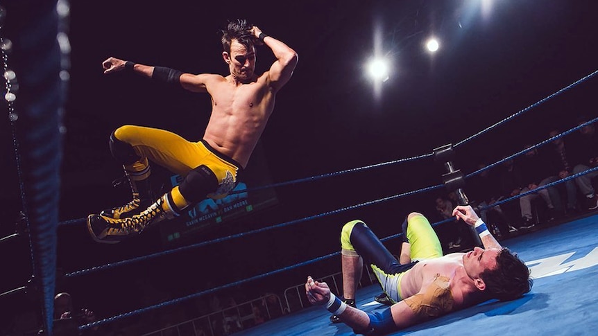 Pro wrestling performers mid air performing slam action.