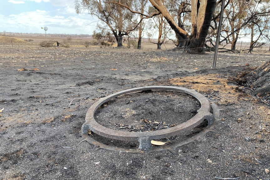 A large metal ring sits on fire ground