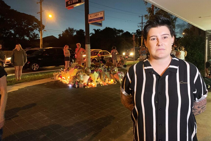 Nikki Kemp stands in front of the candlelight tribute at the scene of the fatal crash.