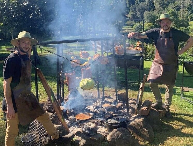 Two men standing outside at a roasting pit