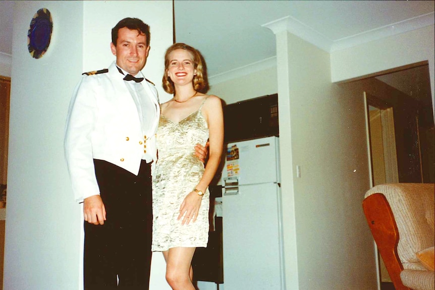 Old photograph of man in a formal navy outfit and woman in a short gold dress posing in living room