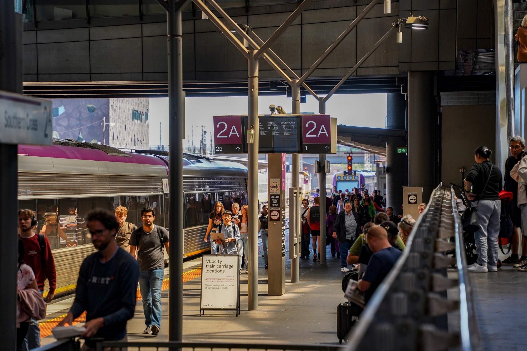 A few dozen people walking on a train platform