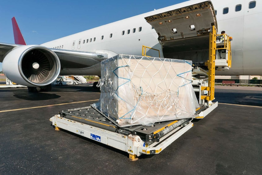 A large container on the tarmac next to a plane.
