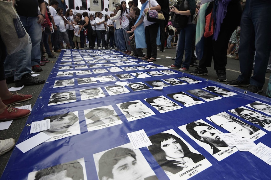 Photo of protestors gathered around images of missing Argentinians during march in 2015.