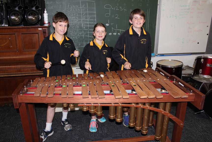 Two boys and a girl playing a marimba in a classroom