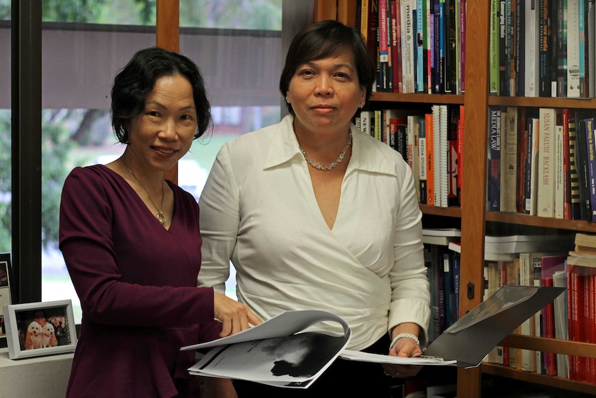 Dr Wendy Li and Dr Amy Forbes examine a folder with papers inside it