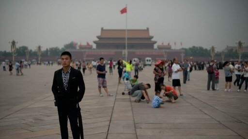 A plain-clothes policeman follows suspected journalists in Tiananmen Square.