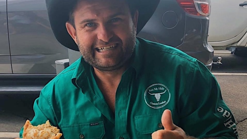 Shaun Pyne eating a meat pie with a black hat on and green shirt
