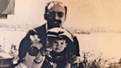 A grainy black and white photo shows a couple holding a young child.