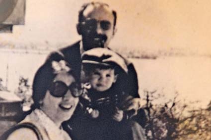 A grainy black and white photo shows a couple holding a young child.