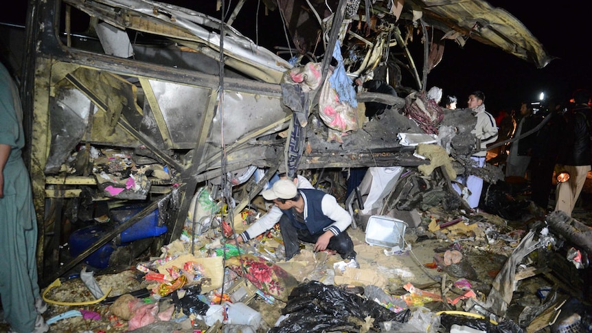 Pakistanis search the wreckage of destroyed bus