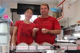 A Chinese woman and Australian man hold dumplings in their hands