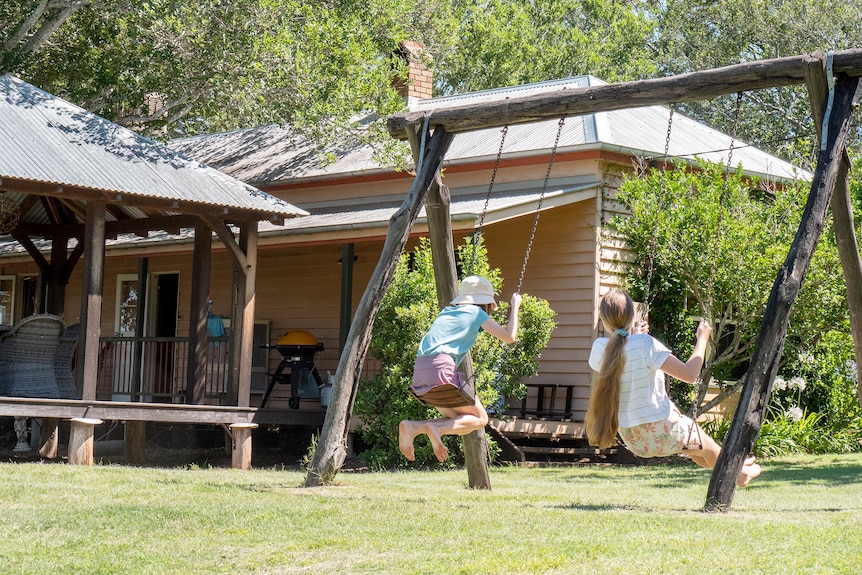 Two children swinging in a country setting.