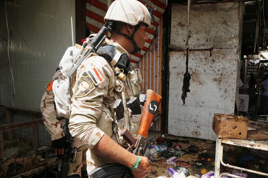 A member of Iraqi security forces inspects the site of a suicide bomb.