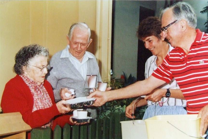 Two Meals on Wheels volunteers hand food over to two elderly residents