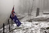 An Australian flag sits in a fence after snow fell in Kinglake