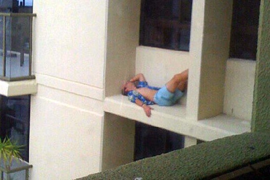A Gold Coast schoolie lies on the ledge of an apartment block.