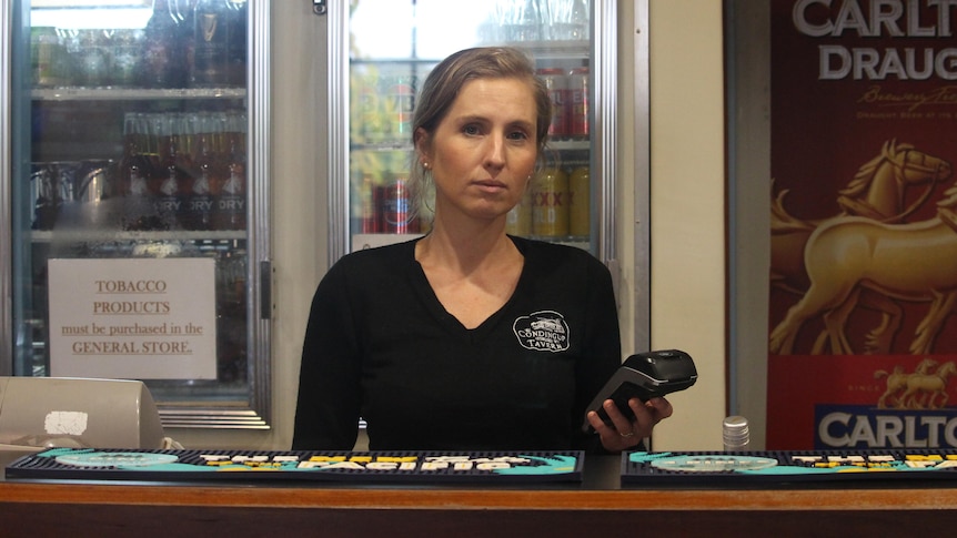 She stands at the bar holding an EFTPOS machine