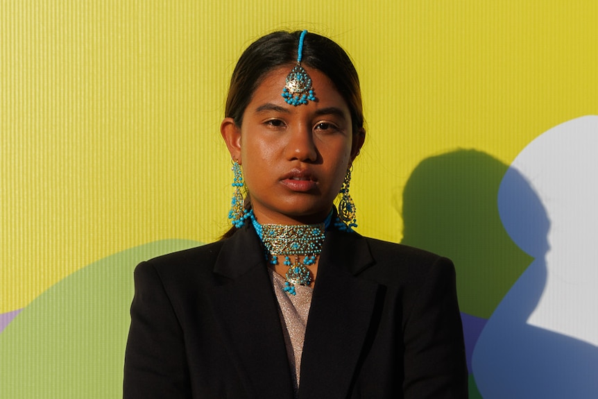 A young woman wearing torquise headpiece and jewellery. 